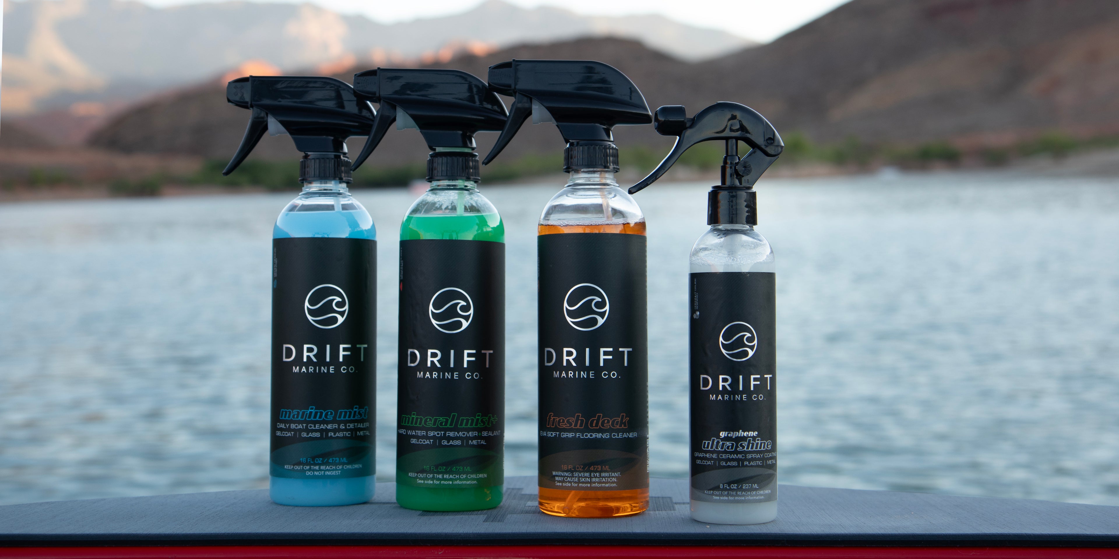 Four bottles of DRIFT Marine Co. products on a surface with a scenic background.
